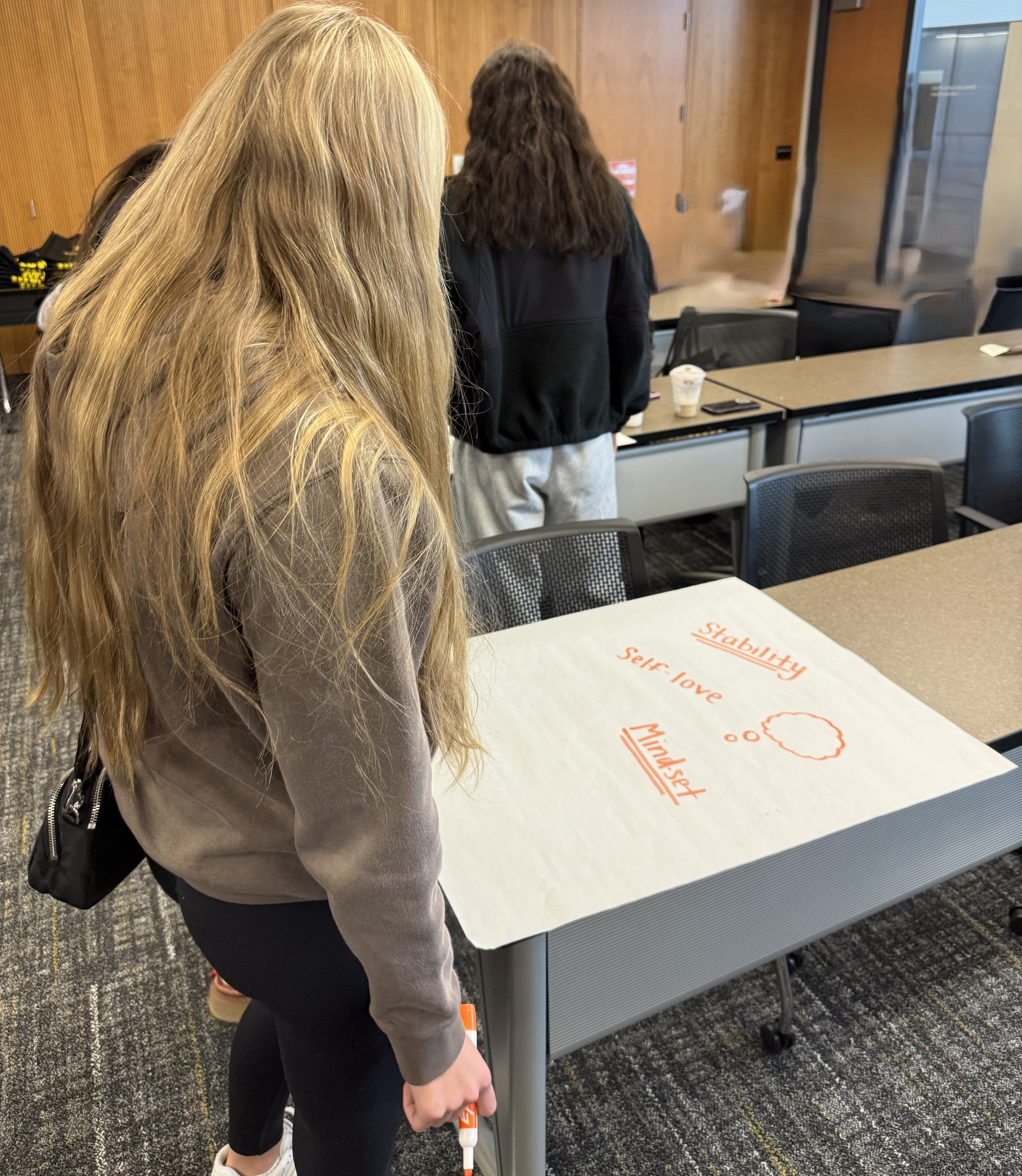 Iowa teen standing in front of a poster, mid-creation that states stability, self-love, and mindset 